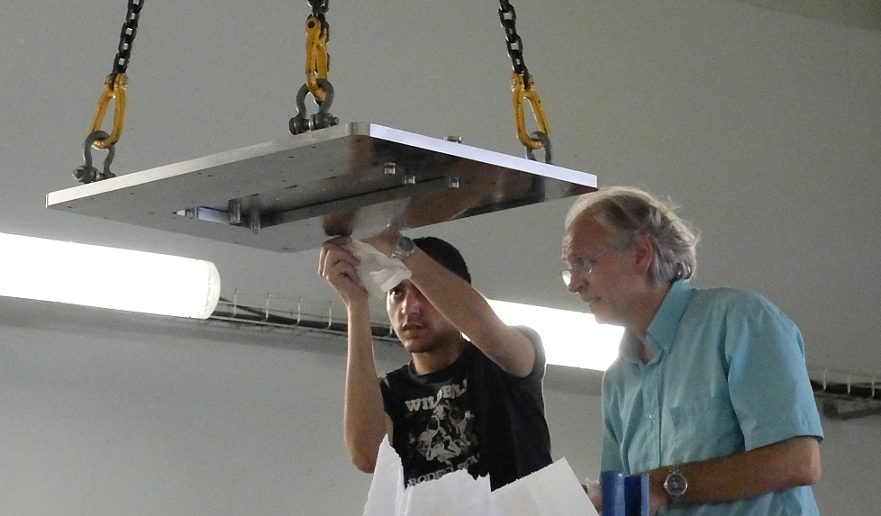 photo of two people cleaning a large suspended rectangular flange