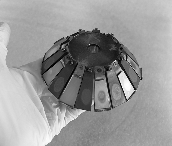Photo of gloved hand holding a conical target block typical for multi beam sputter deposition on circular substrates, with 10 targets of material A, alternating with 10 targets of material B